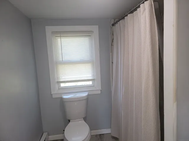 a white toilet sitting in a bathroom next to a window