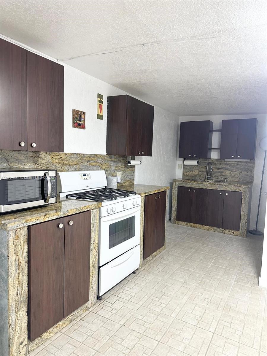 2753 West 68th Place Hialeah, FL 33016 - Photo 6 of 10 a kitchen with stainless steel appliances granite countertop a sink stove and cabinets