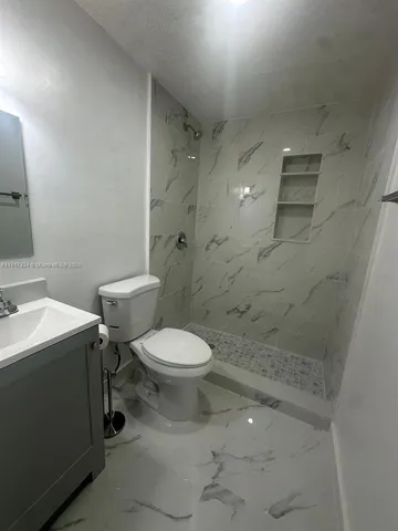 a white toilet sitting next to a bathroom sink and vanity