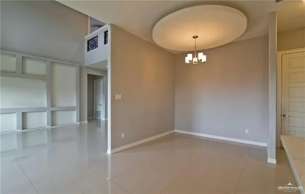 an empty room with a chandelier fan and entryway