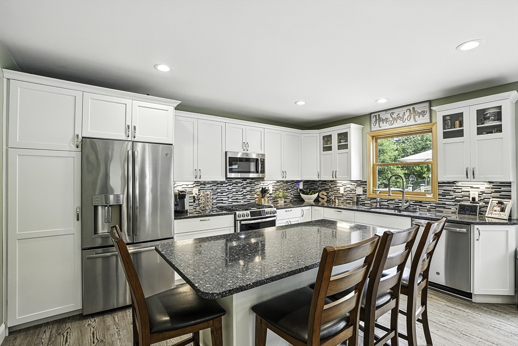 133 Rowley Hill Road Sterling, MA 01564 - Photo 9 of 41 a kitchen with refrigerator a stove and chairs
