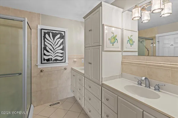 a bedroom with a bed a chandelier and a flat tv screen on dresser