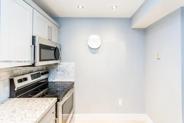 a kitchen with granite countertop white cabinets stainless steel appliances and a sink