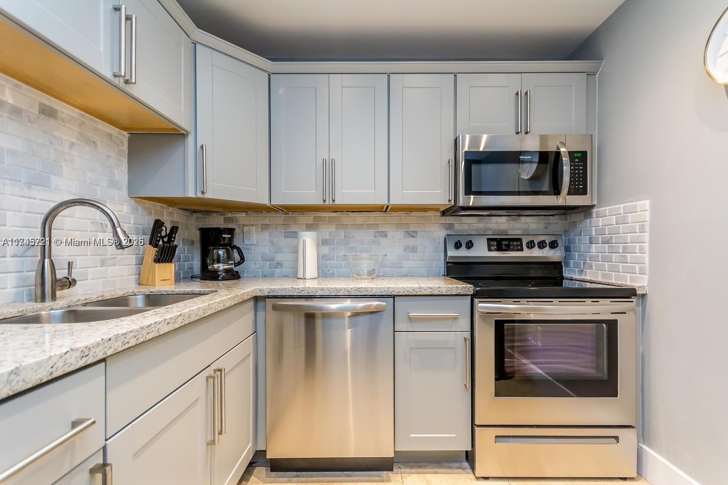 17620 Atlantic Boulevard, Unit 519 Sunny Isles Beach, FL 33160 - Photo 22 of 33 a kitchen with stainless steel appliances granite countertop a stove a sink and a microwave