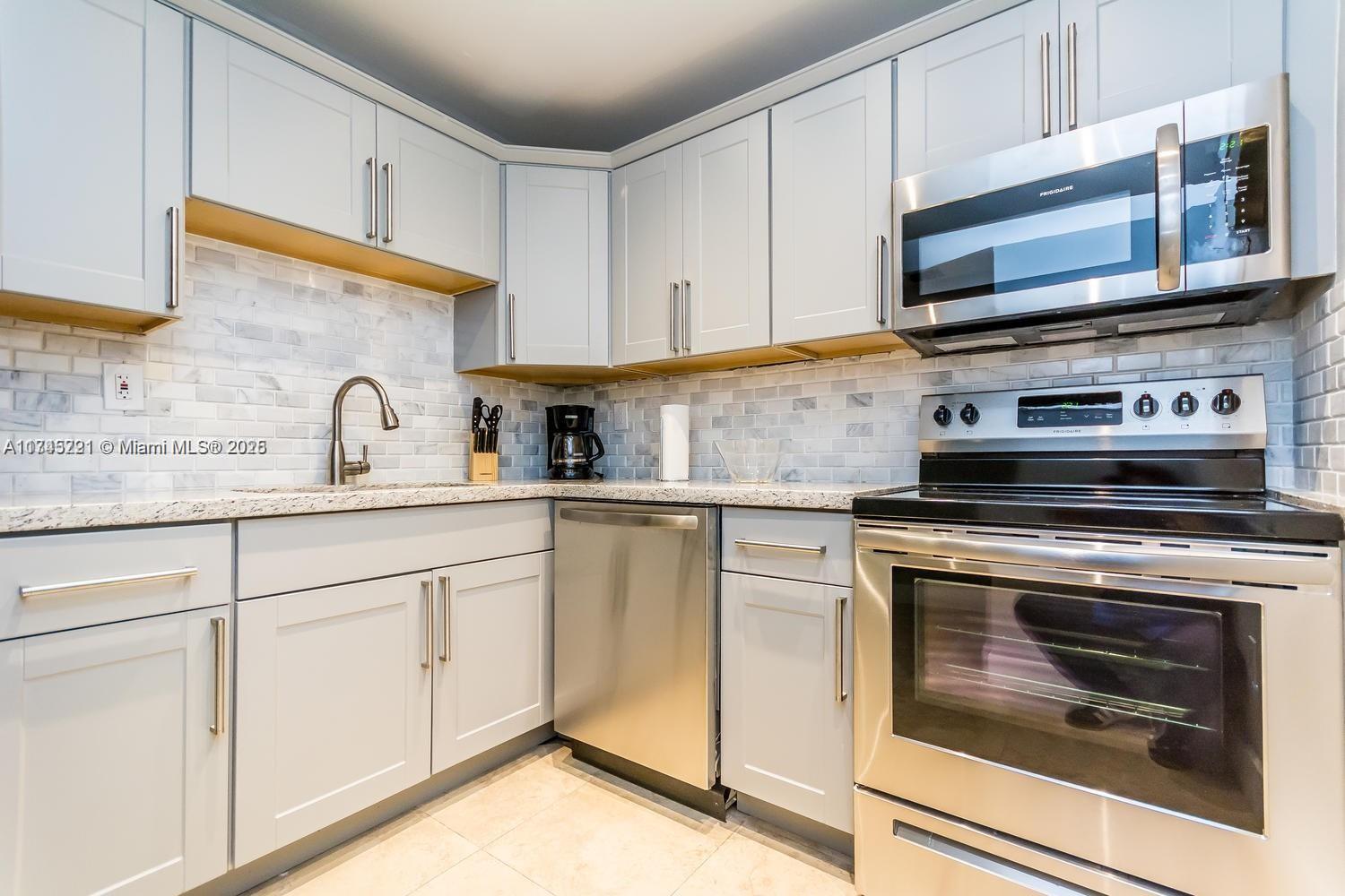 17620 Atlantic Boulevard, Unit 519 Sunny Isles Beach, FL 33160 - Photo 24 of 33 a kitchen with granite countertop white cabinets stainless steel appliances and a sink