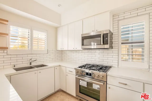 a kitchen with granite countertop cabinets stainless steel appliances a sink and a window