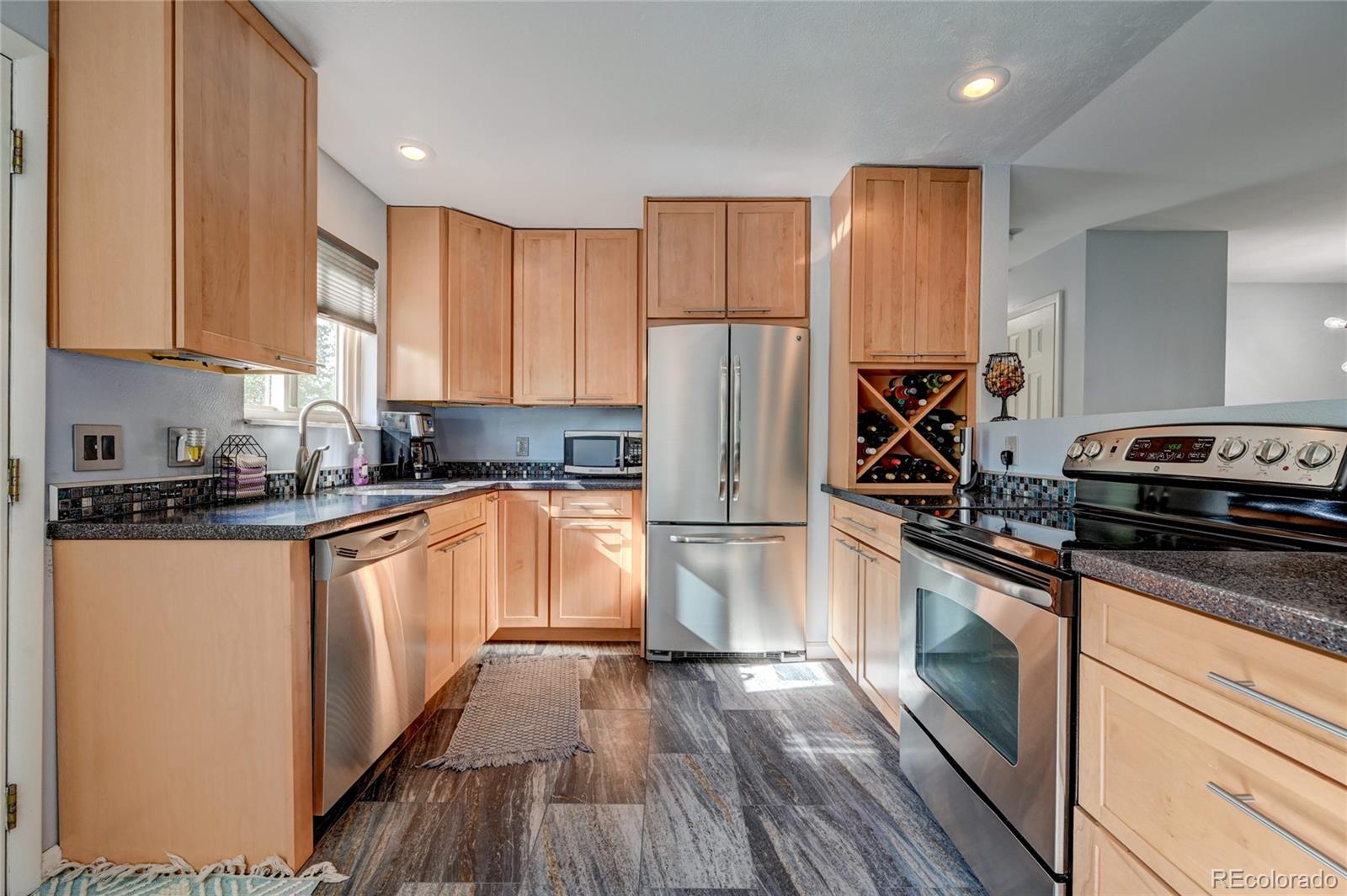 a kitchen with granite countertop a refrigerator a sink and wooden floors