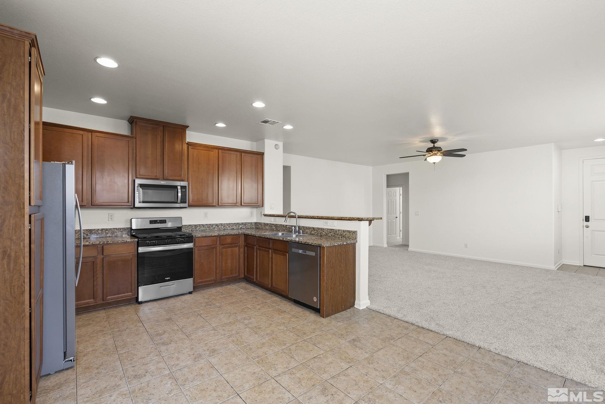 9130 Andraste Way Reno, NV 89506 - Photo 11 of 19 a large kitchen with stainless steel appliances granite countertop a stove and a refrigerator