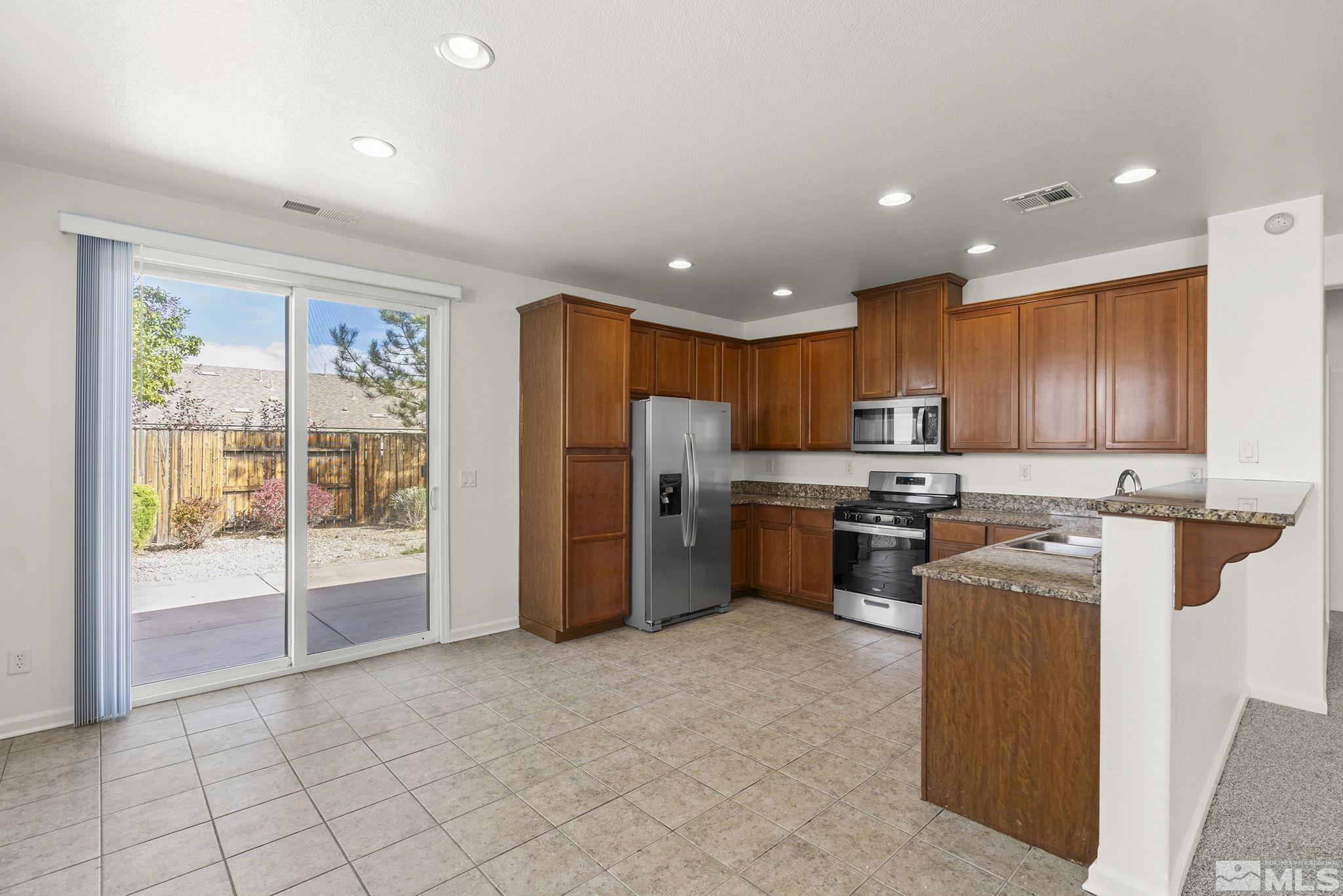 9130 Andraste Way Reno, NV 89506 - Photo 9 of 19 a kitchen with stainless steel appliances granite countertop a refrigerator and a stove top oven