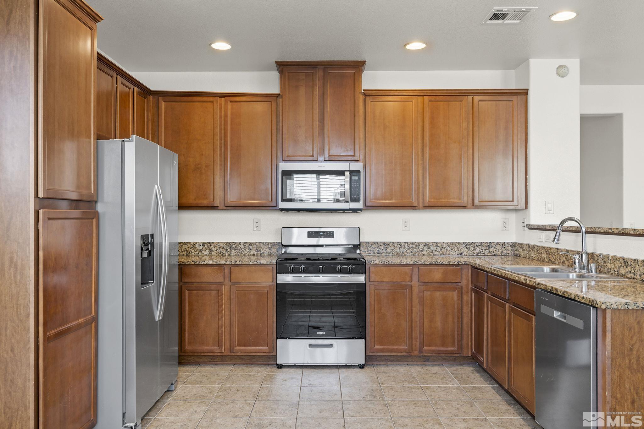 9130 Andraste Way Reno, NV 89506 - Photo 10 of 19 a kitchen with stainless steel appliances granite countertop a refrigerator and a sink
