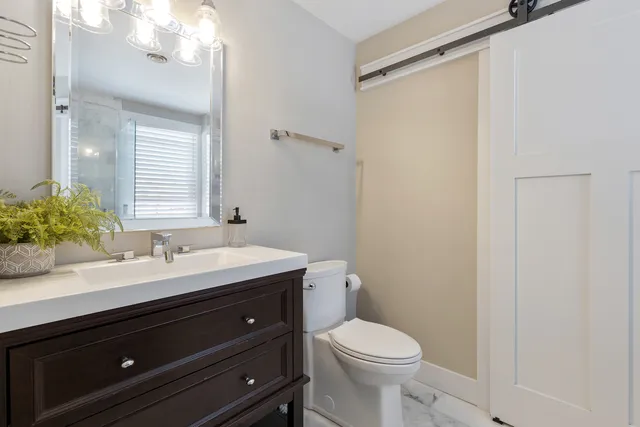 a bathroom with a sink a toilet a mirror and a shower