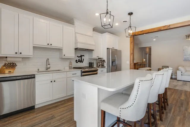 a kitchen with stainless steel appliances a table chairs refrigerator and cabinets