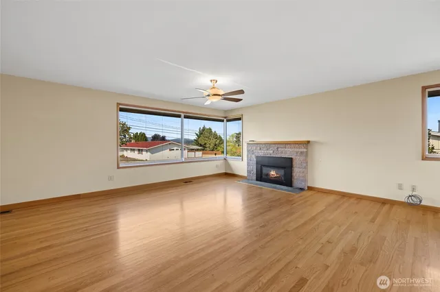 a view of a livingroom with furniture a fireplace wooden floor and windows