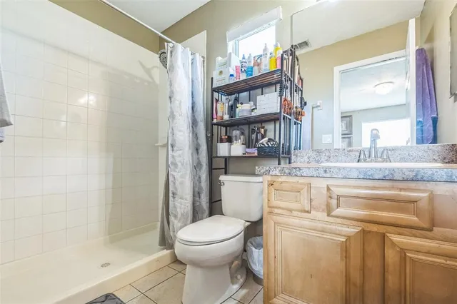 a bathroom with a granite countertop sink a toilet a mirror and shower