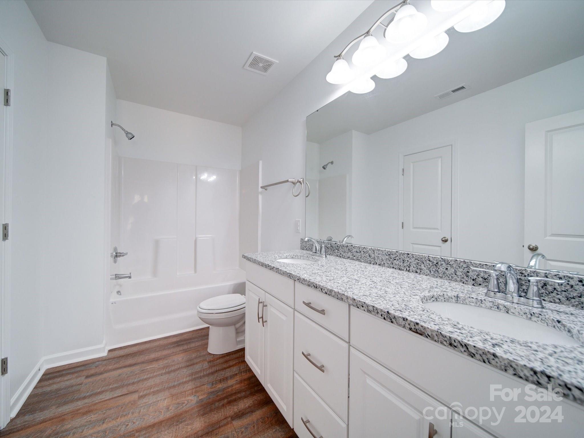 147 Lambeth Road Thomasville, NC 27360 - Photo 18 of 33 a bathroom with a granite countertop double vanity sink a mirror and a toilet