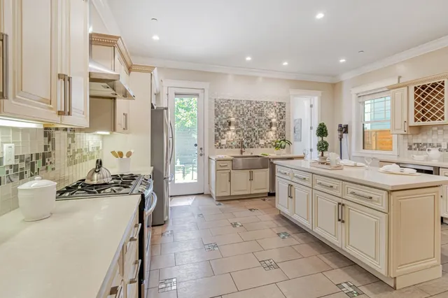 a kitchen with a stove a sink a refrigerator and white cabinets with wooden floor