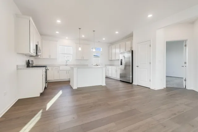 a large white kitchen with stainless steel appliances lots of white cabinets