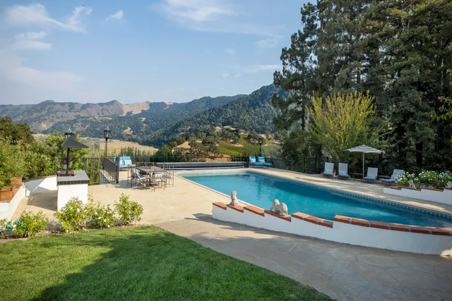a view of a big house with a big yard plants and large trees