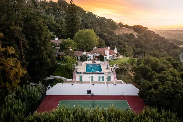 an aerial view of a house with a yard and greenery