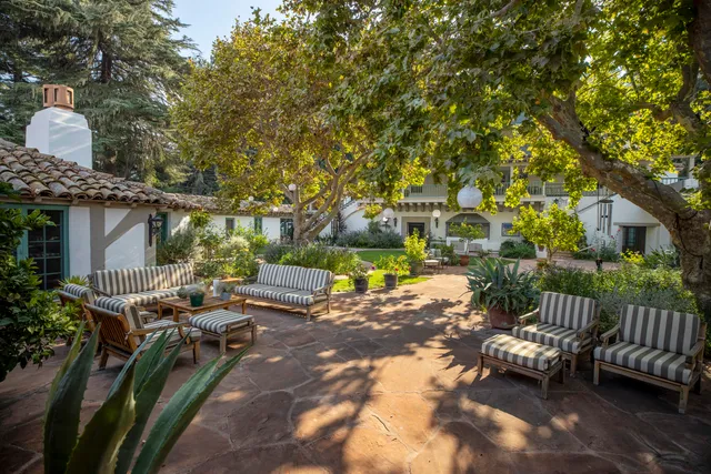 a view of a house with table and chairs under an umbrella