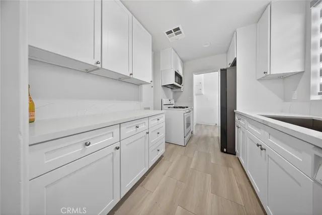 a kitchen with stainless steel appliances a stove a sink and white cabinets