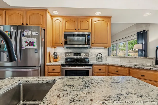a kitchen with stainless steel appliances granite countertop a refrigerator a stove top oven and sink