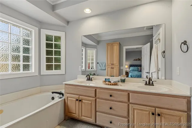 a bathroom with a tub a double vanity sink a window and mirror