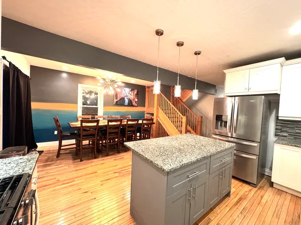 a kitchen with stainless steel appliances kitchen island granite countertop a table chairs and a refrigerator