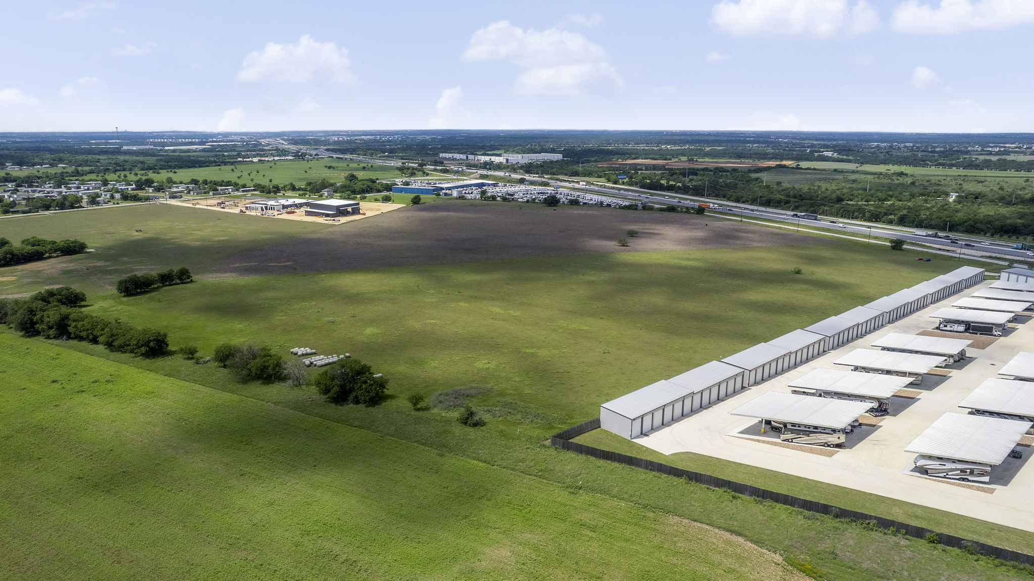 6100 Interstate 35 Georgetown, TX 78626 - Photo 9 of 11 Expansive land parcel featuring a large, undeveloped grassy area, adjacent to a storage facility with multiple units and covered parking structures