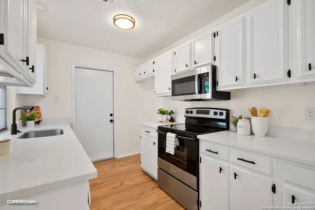 a kitchen with granite countertop white cabinets and stainless steel appliances