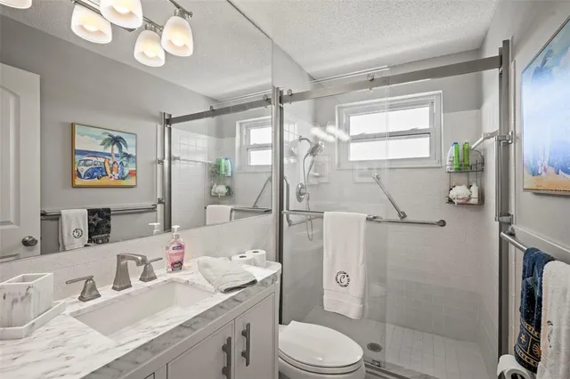 a bathroom with a granite countertop sink mirror vanity shower and a toilet