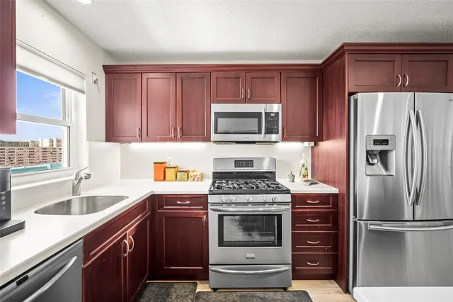 a kitchen with a refrigerator stove and sink with wooden cabinet