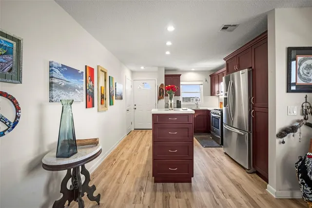 a kitchen with stainless steel appliances kitchen island granite countertop a refrigerator a stove and a wooden floors