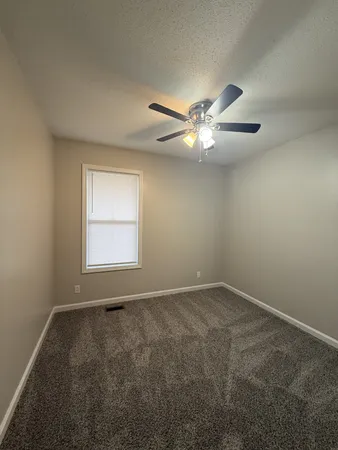 an empty room with a window and a fan