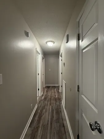 a view of a hallway with wooden floor and a bathroom