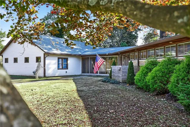 a view of a house with a yard and a large tree
