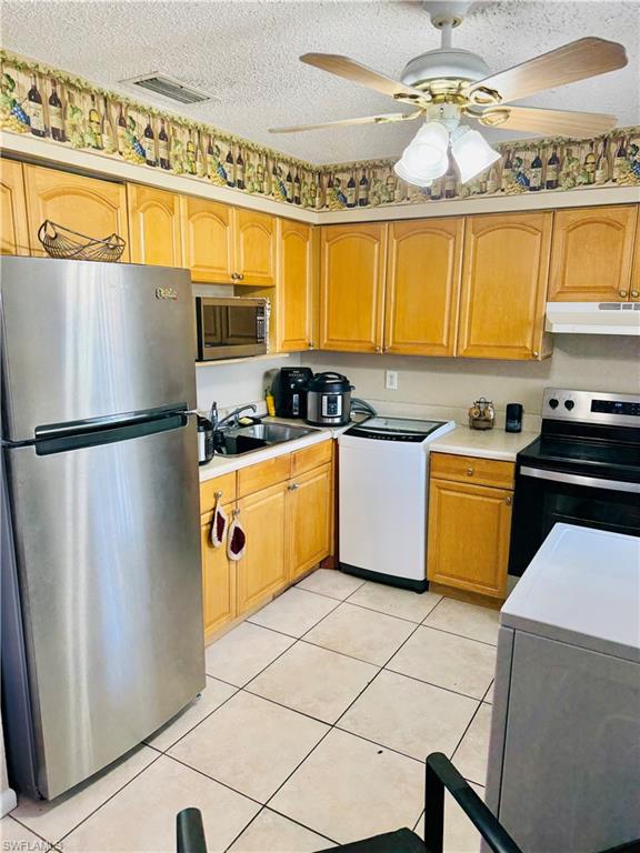 3325 Airport Road North, Unit R6 Naples, FL 34105 - Photo 5 of 11 Kitchen featuring stainless steel appliances, light countertops, a ceiling fan, light tile patterned flooring, and a textured ceiling