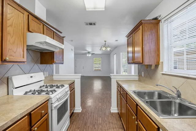 a kitchen that has a sink wooden floor stainless steel appliances and cabinets