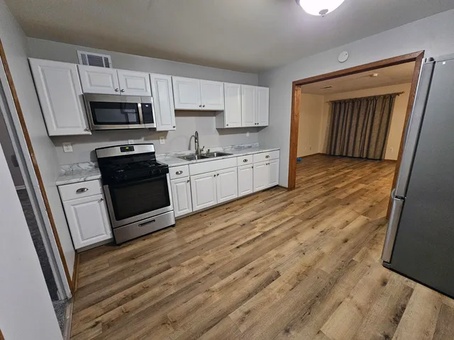 a kitchen with granite countertop a refrigerator stove and sink