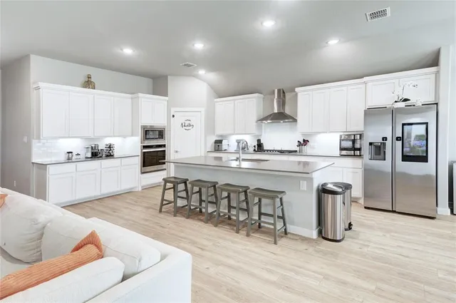 a kitchen with stainless steel appliances kitchen island granite countertop a table chairs sink refrigerator and cabinets