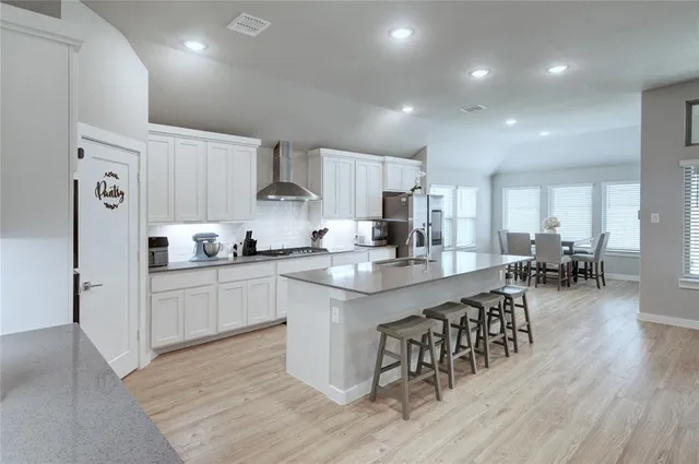a kitchen with white cabinets and chairs