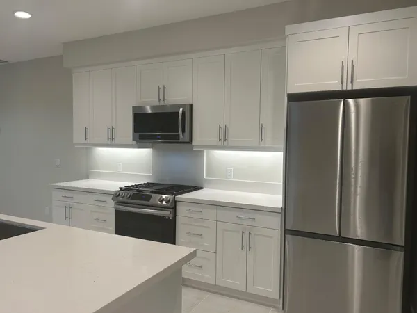 a kitchen with stainless steel appliances a sink a stove a microwave a counter top space and cabinets