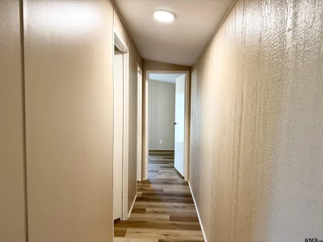 a view of a hallway with wooden floor and a bathroom