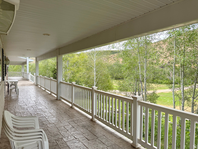 1133 Paris Canyon Road Paris, ID 83261 - Photo 35 of 75 Expansive covered porch featuring stamped concrete flooring, white balustrade railing, recessed ceiling lighting, and exterior wall sconces
