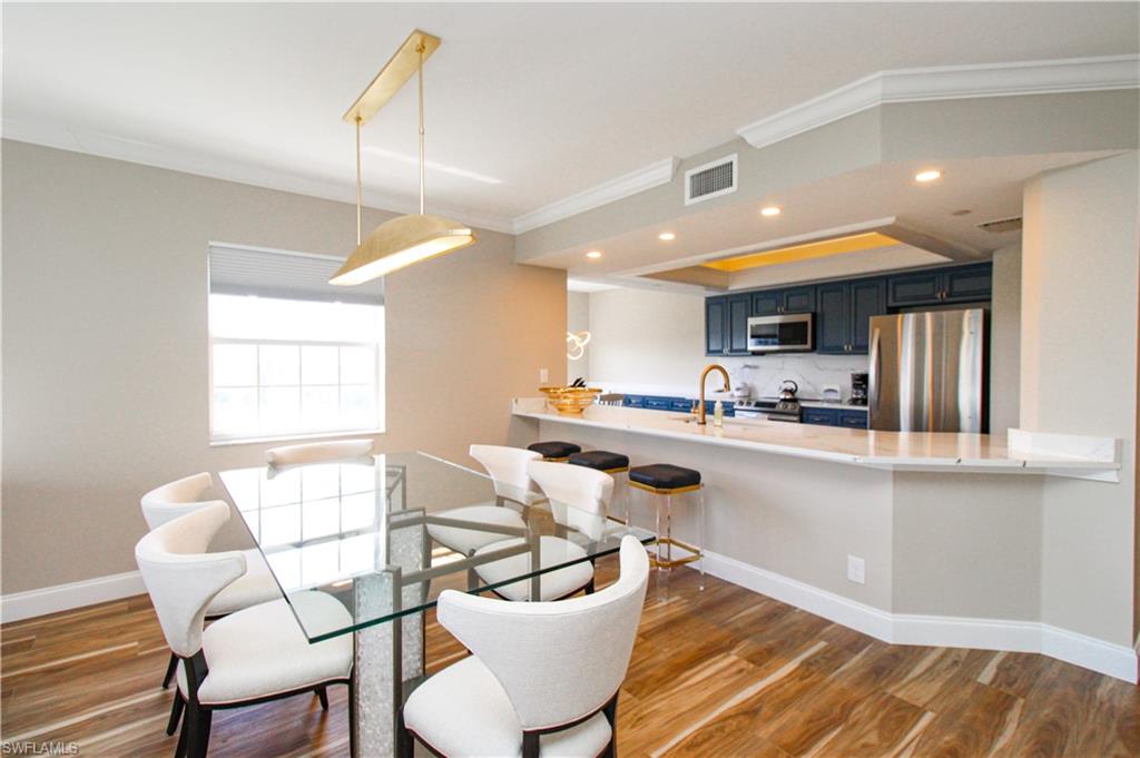 35 Bluebill Avenue, Unit B702 Naples, FL 34108 - Photo 21 of 50 a kitchen with a dining table chairs and white cabinets