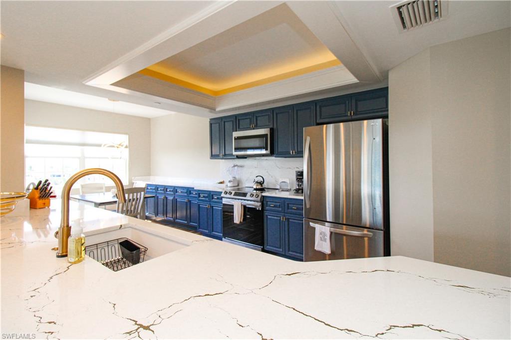 35 Bluebill Avenue, Unit B702 Naples, FL 34108 - Photo 26 of 50 a kitchen with stainless steel appliances kitchen island a refrigerator sink and stove