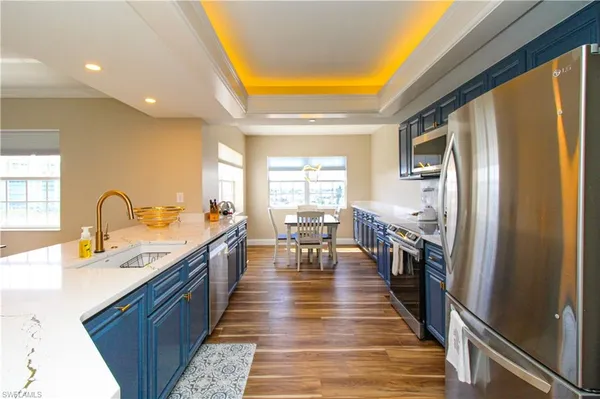 a large kitchen with stainless steel appliances granite countertop a refrigerator a sink dishwasher a dining table and chairs with wooden floor