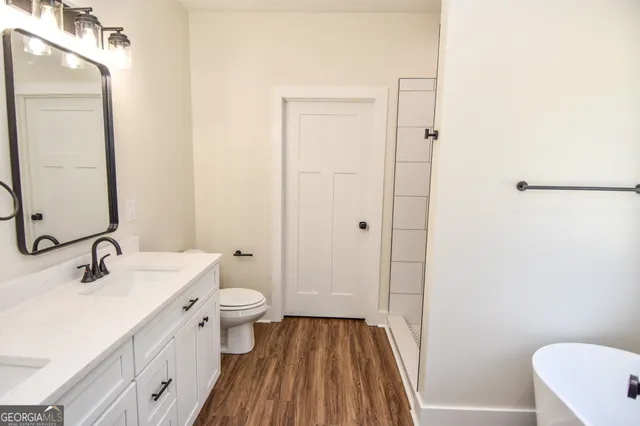 an empty room with wooden floor chandelier fan and windows