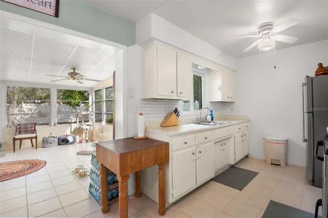 a large white kitchen with a window and refrigerator