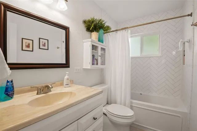 a bathroom with a granite countertop sink a toilet and shower